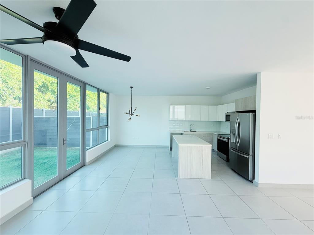 A modern kitchen and dining area features white cabinetry, a central island, and large windows — Urb Riviera Court 57, BAYAMON, PR