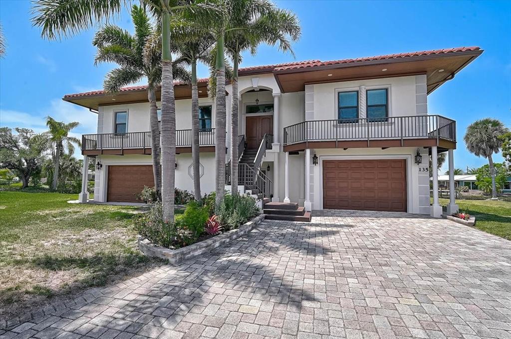A two-story house with a tiled roof, two garages, and a balcony over a paved driveway — 135 TINA ISLAND DRIVE, OSPREY, FL