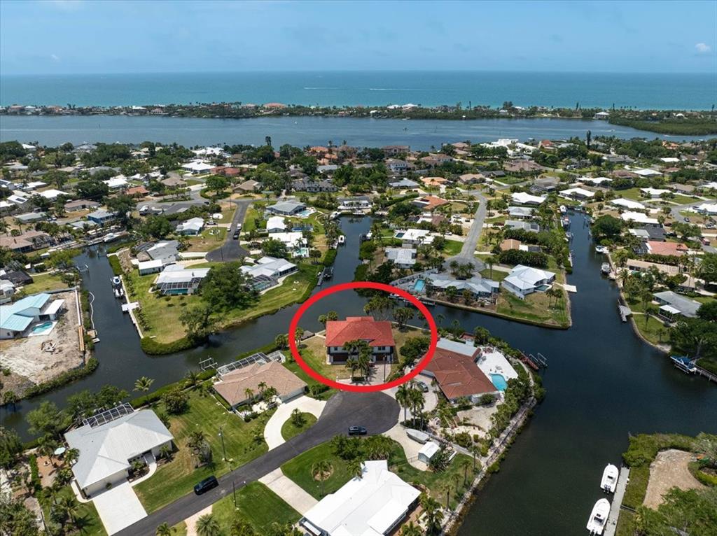 An aerial view shows a house with a red roof situated on a canal — 135 TINA ISLAND DRIVE, OSPREY, FL