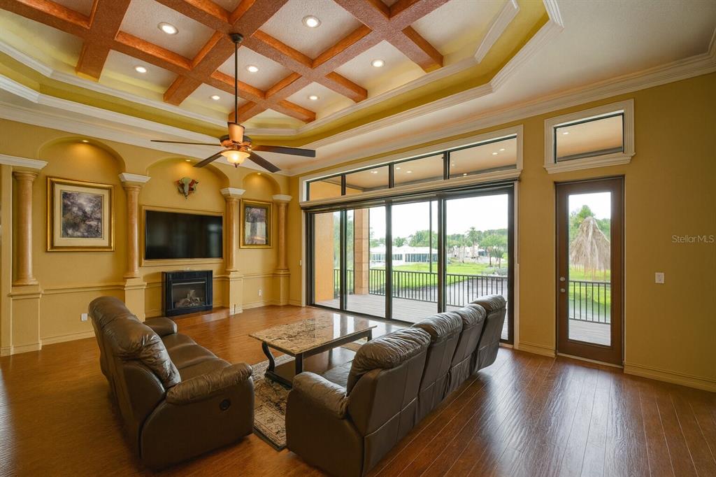 A living room features a coffered ceiling, wood floors, a fireplace, and large sliding glass doors — 135 TINA ISLAND DRIVE, OSPREY, FL