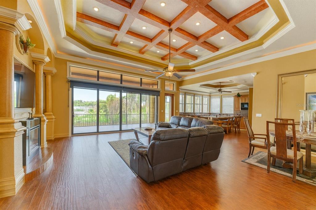 A living room with a coffered ceiling, wood floors, and sliding glass doors to a balcony — 135 TINA ISLAND DRIVE, OSPREY, FL