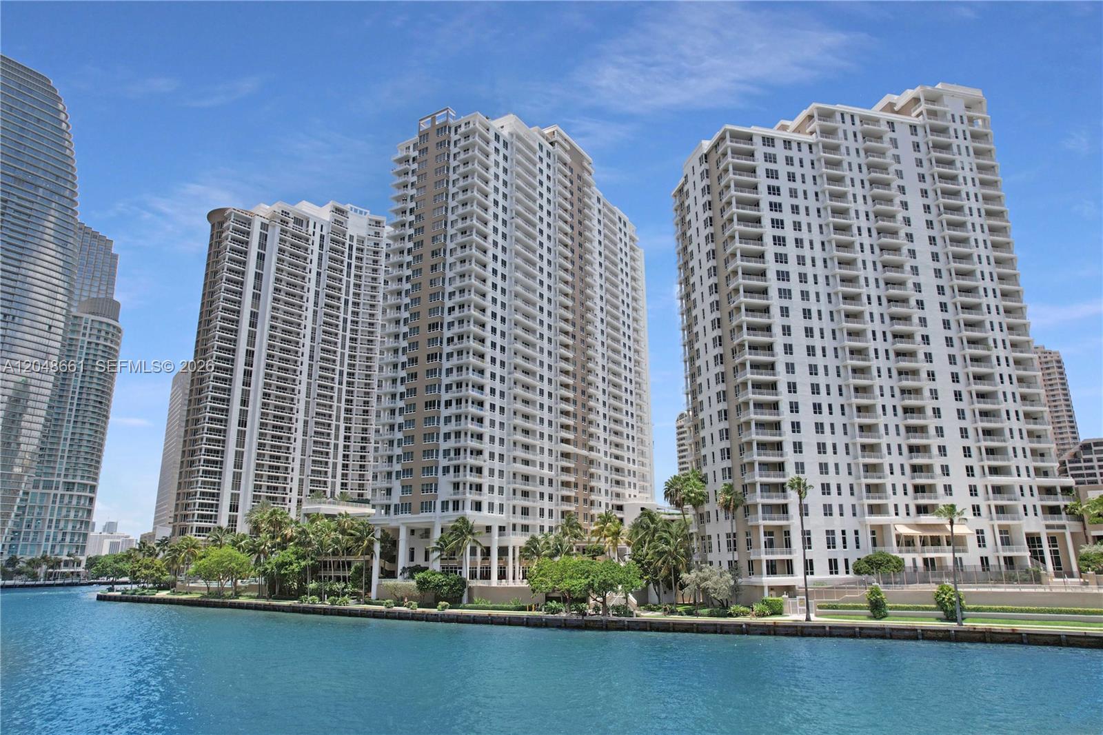 Three tall residential high-rise buildings stand along a waterfront under a clear blue sky — 801 Brickell Key Blvd # 2210, Miami FL 33131, MIAMI, FL