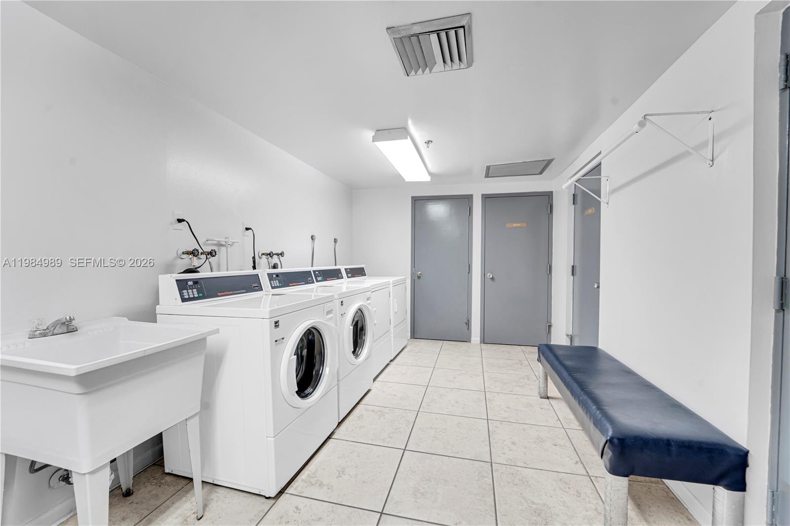 A laundry room features white appliances, a utility sink, a bench, and tile flooring — 919 Hillcrest Dr # 210, Hollywood FL 33021, HOLLYWOOD, FL