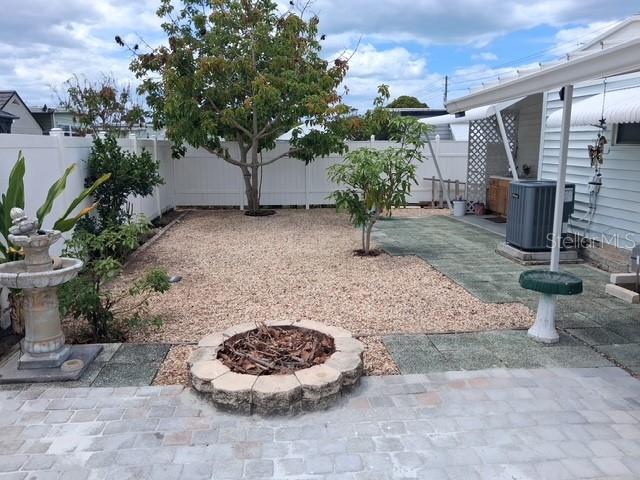A backyard features a gravel area, a stone fire pit, a patio, and two trees — 5148 DARLINGTON ROAD, HOLIDAY, FL