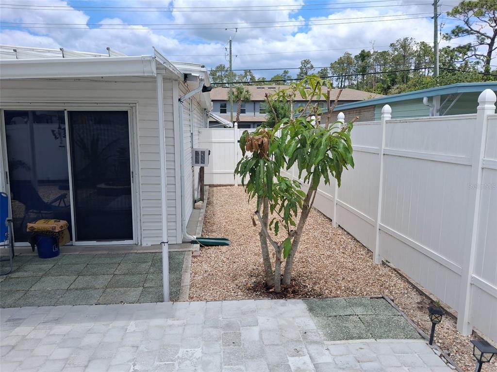 A backyard features a patio, a small tree, and a white vinyl fence — 5148 DARLINGTON ROAD, HOLIDAY, FL