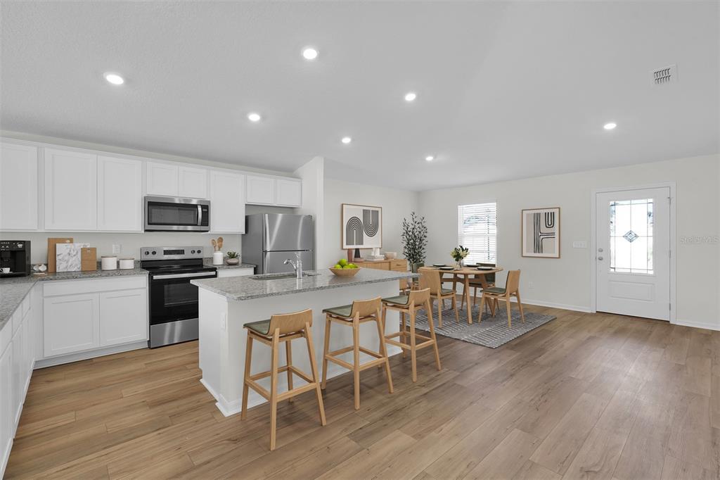A kitchen with white cabinets, stainless steel appliances, and a granite-topped island with bar stools — 2517 SW 165TH STREET ROAD, OCALA, FL