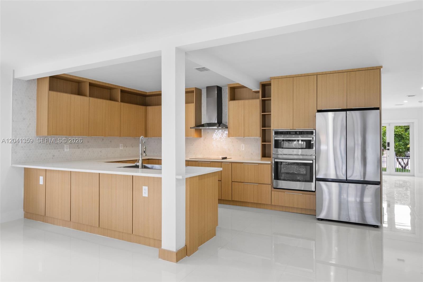 A modern kitchen features light wood cabinetry, stainless steel appliances, and white countertops — 2940 SW 12th St, Miami FL 33135, MIAMI, FL
