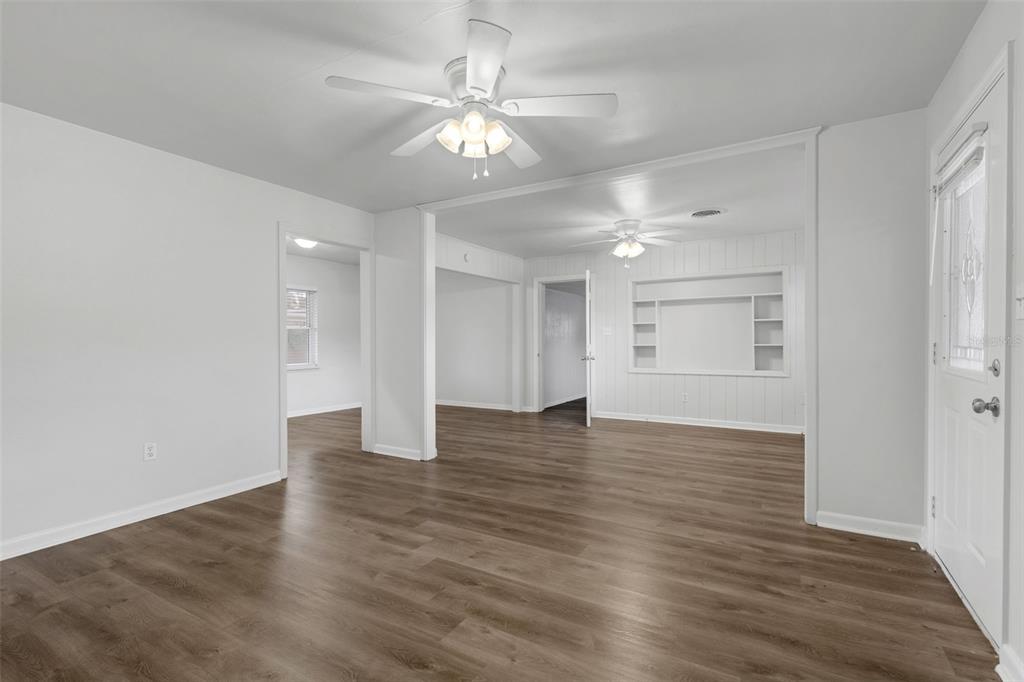 An interior view of a living room with white walls, wood-look flooring, and ceiling fans — 203 E LAKEVIEW AVENUE, EUSTIS, FL