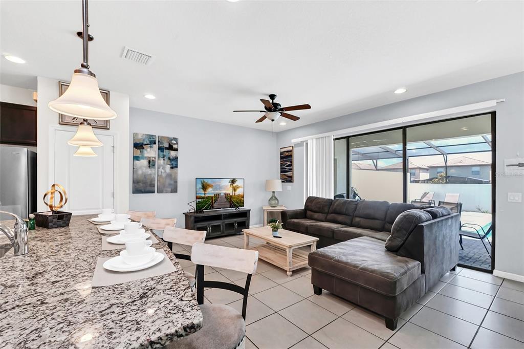 A kitchen with dark cabinets and granite countertops opens to a living area with tile — 8930 SYDNEY AVENUE, KISSIMMEE, FL
