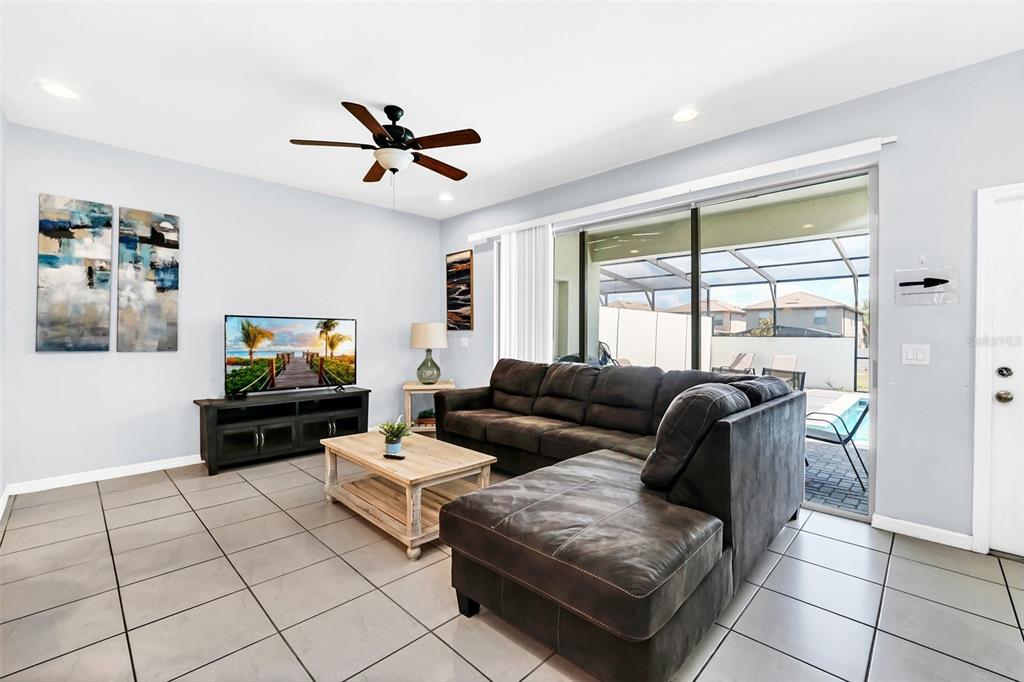 A living room with a sectional sofa, television, and an adjacent kitchen island with seating — 8930 SYDNEY AVENUE, KISSIMMEE, FL