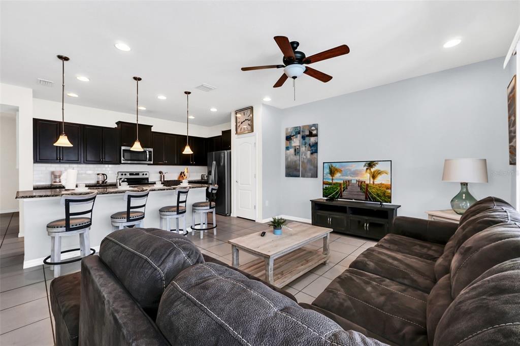 A living room features a brown sofa, a wooden coffee table, and a television console — 8930 SYDNEY AVENUE, KISSIMMEE, FL