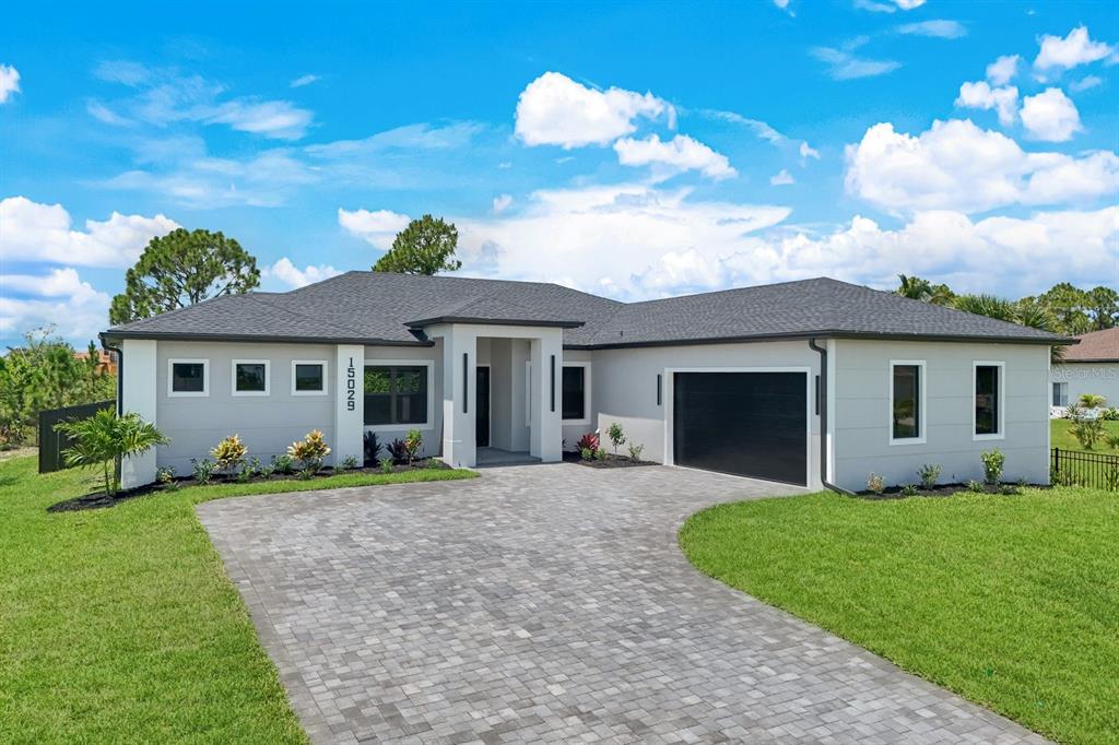 A modern single-story house with a gray exterior, dark roof, and a paved driveway — 15029 ACORN CIRCLE, PORT CHARLOTTE, FL