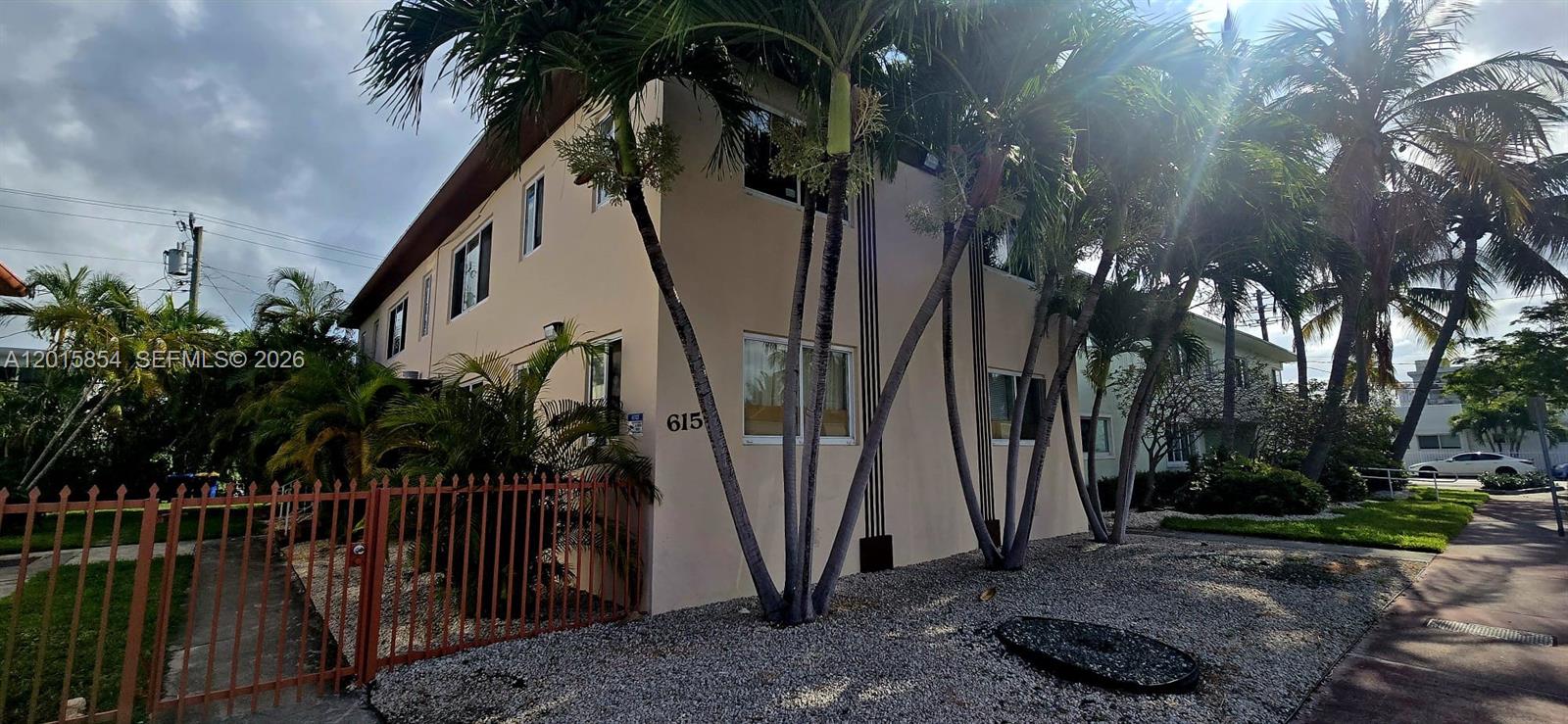 A two-story tan apartment building with palm trees and a red metal fence — 615 82nd St # 1, Miami Beach FL 33141, MIAMI BEACH, FL