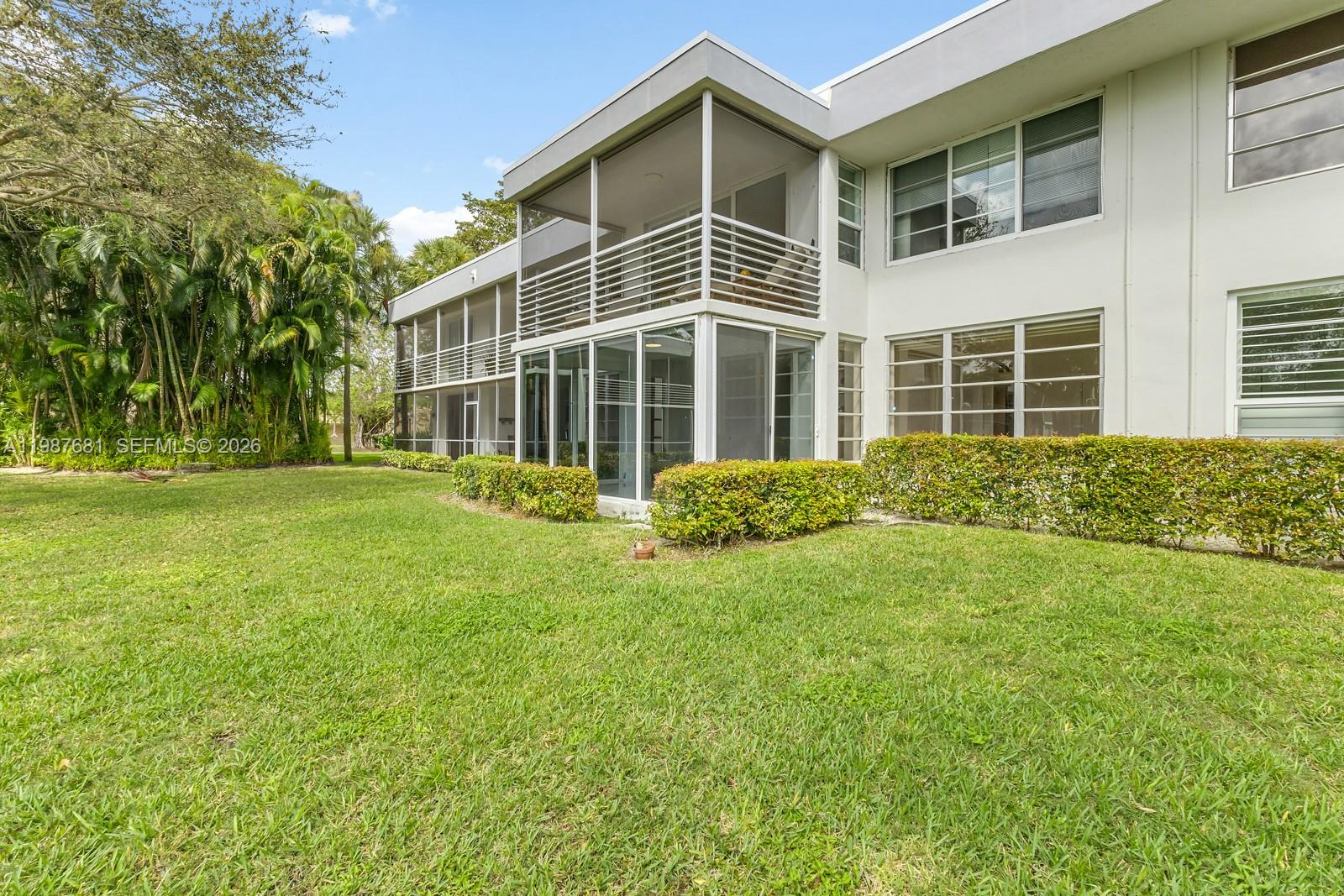 The exterior of a two-story apartment building features screened-in balconies and large windows — 4280 Oaks Ter # 102, Pompano Beach FL 33069, POMPANO BEACH, FL