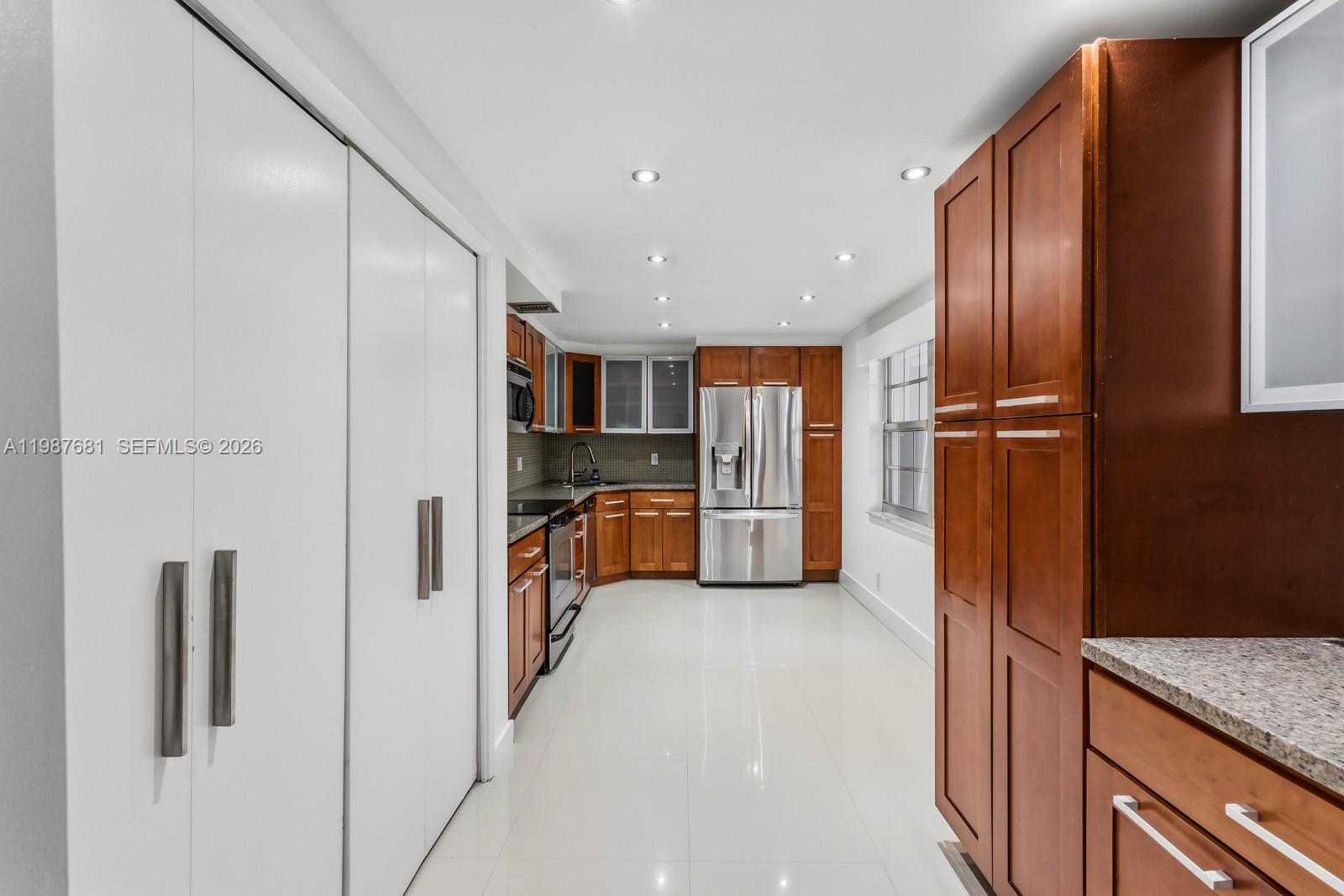 A kitchen features wood cabinets, stainless steel appliances, and white tile flooring — 4280 Oaks Ter # 102, Pompano Beach FL 33069, POMPANO BEACH, FL