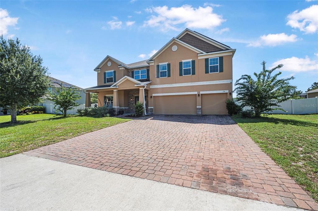 A two-story house with a tan stucco exterior, stone accents, and a brick paver driveway — 120 LOS ARBOR DRIVE, DELAND, FL