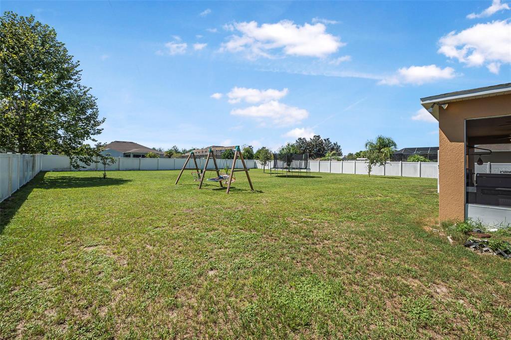 A large, fenced-in backyard features a swing set, a trampoline, and a covered patio area — 120 LOS ARBOR DRIVE, DELAND, FL