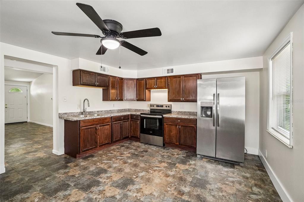 A kitchen with dark wood cabinets, stainless steel appliances, and mottled tile flooring — 9216 W ROBSON STREET, TAMPA, FL