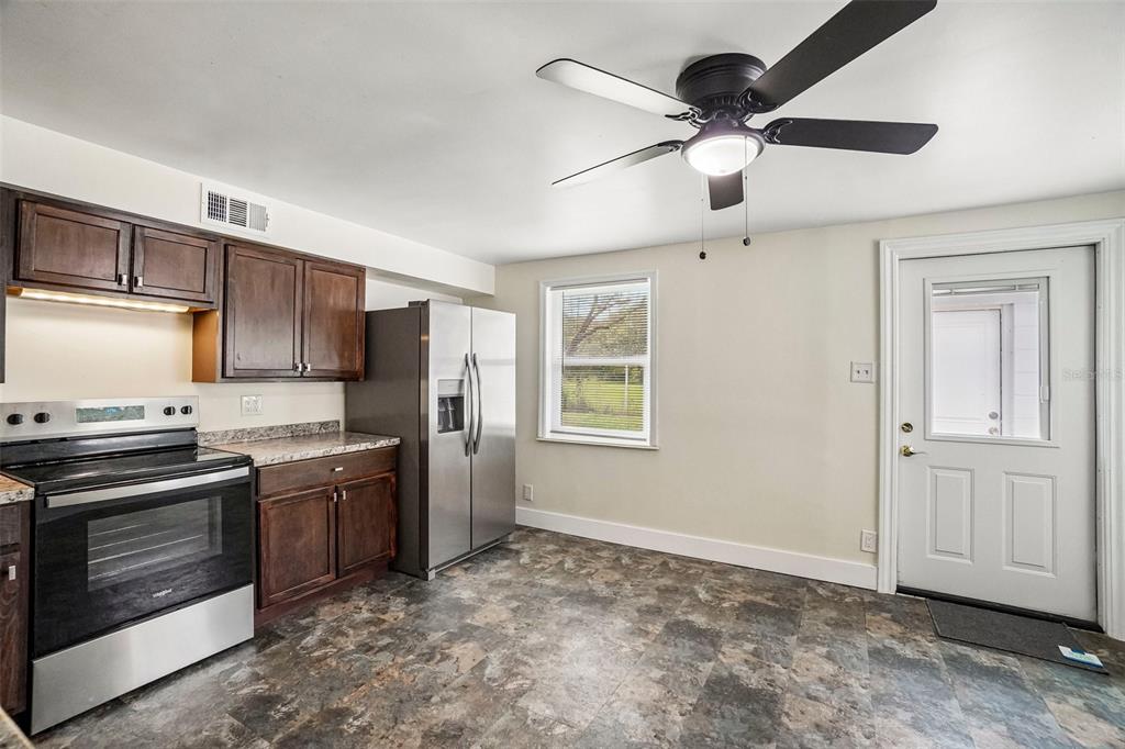 A kitchen features dark wood cabinets, stainless steel appliances, a ceiling fan, and tile flooring — 9216 W ROBSON STREET, TAMPA, FL