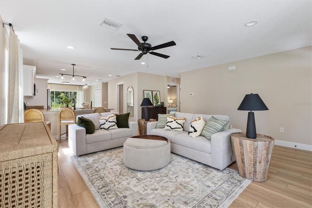 A living room features two light-colored sofas, a round ottoman, and a ceiling fan — 515 E ANDERSON AVENUE, BUSHNELL, FL