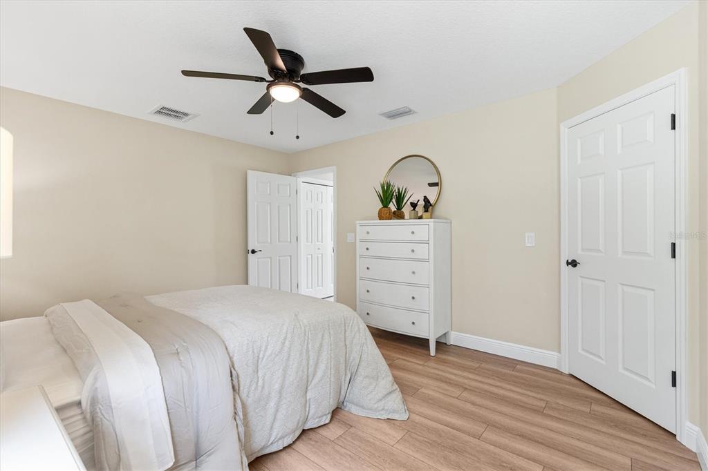 A bedroom features light-colored walls, wood-look flooring, a white dresser, and a ceiling fan — 515 E ANDERSON AVENUE, BUSHNELL, FL