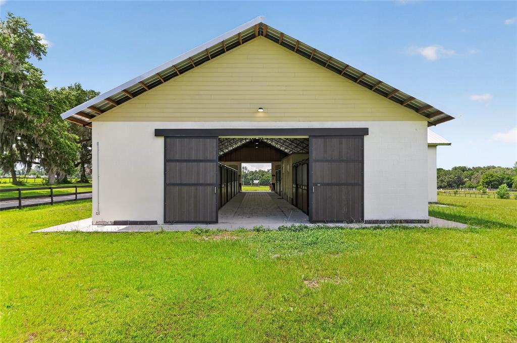 A white barn with a yellow gable and dark sliding doors sits on a lawn — 8544 NW 160TH AVENUE, MORRISTON, FL
