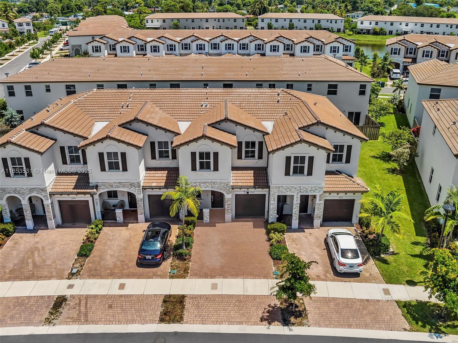 An aerial view shows a row of multi-story townhouses with tiled roofs and paved driveways — 12929 NW 24th Ave, Miami FL 33167, MIAMI, FL