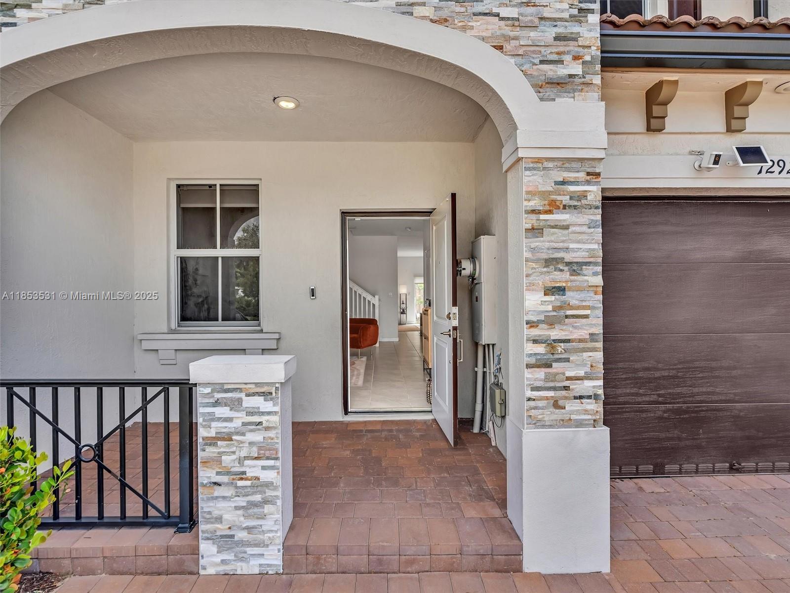 The exterior view shows a covered entryway with stone pillars, a brick porch, and a door — 12929 NW 24th Ave, Miami FL 33167, MIAMI, FL