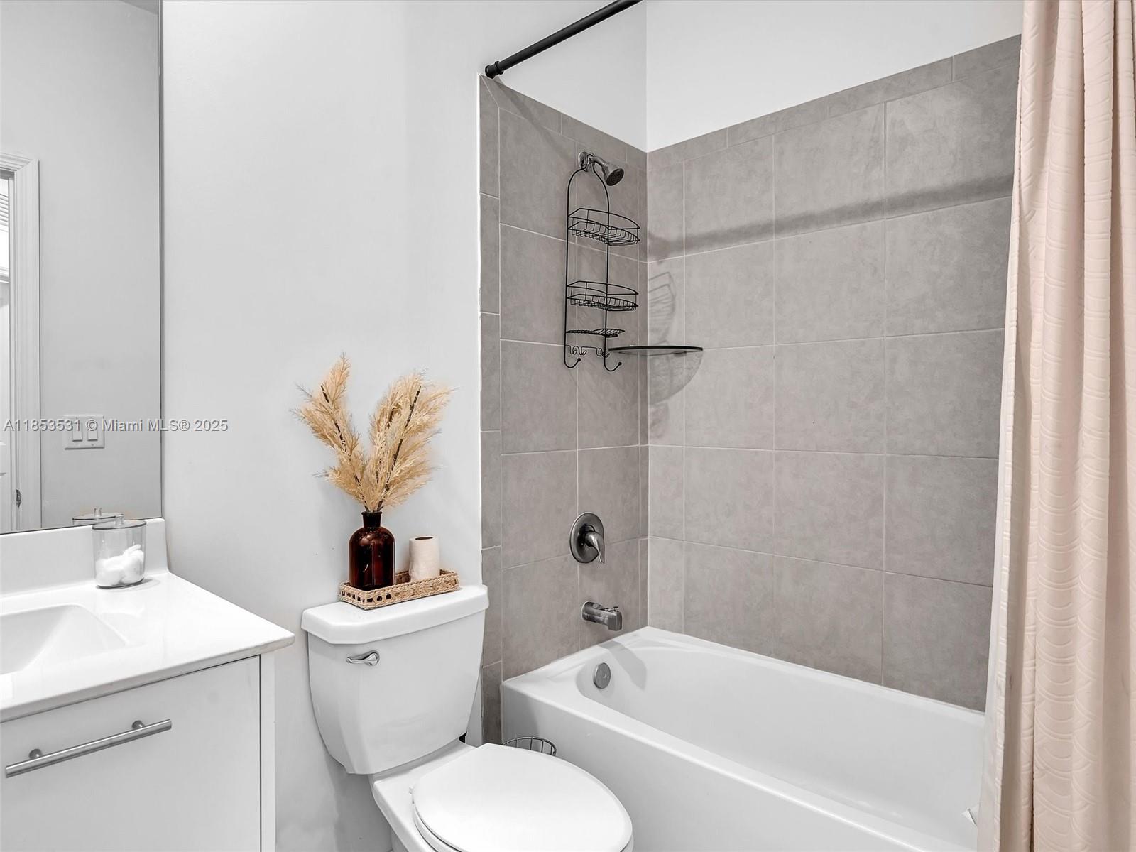 A bathroom features a white vanity, a toilet, and a bathtub with gray tiled walls — 12929 NW 24th Ave, Miami FL 33167, MIAMI, FL