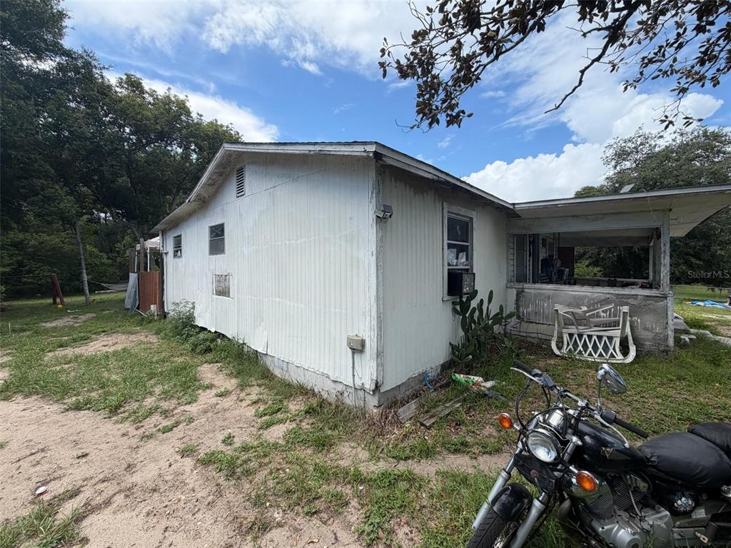 A side view of a weathered, white-sided house with a porch and a parked motorcycle — 1724 S US 301, SUMTERVILLE, FL