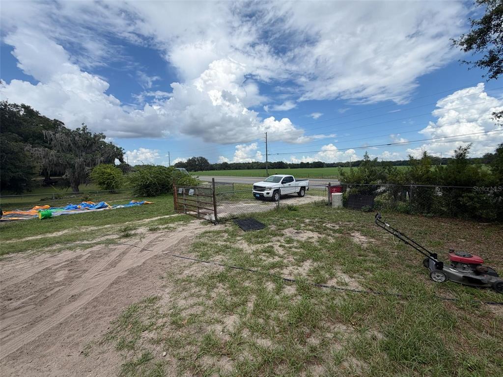 A dirt driveway leads to a metal gate and a white pickup truck outdoors — 1724 S US 301, SUMTERVILLE, FL
