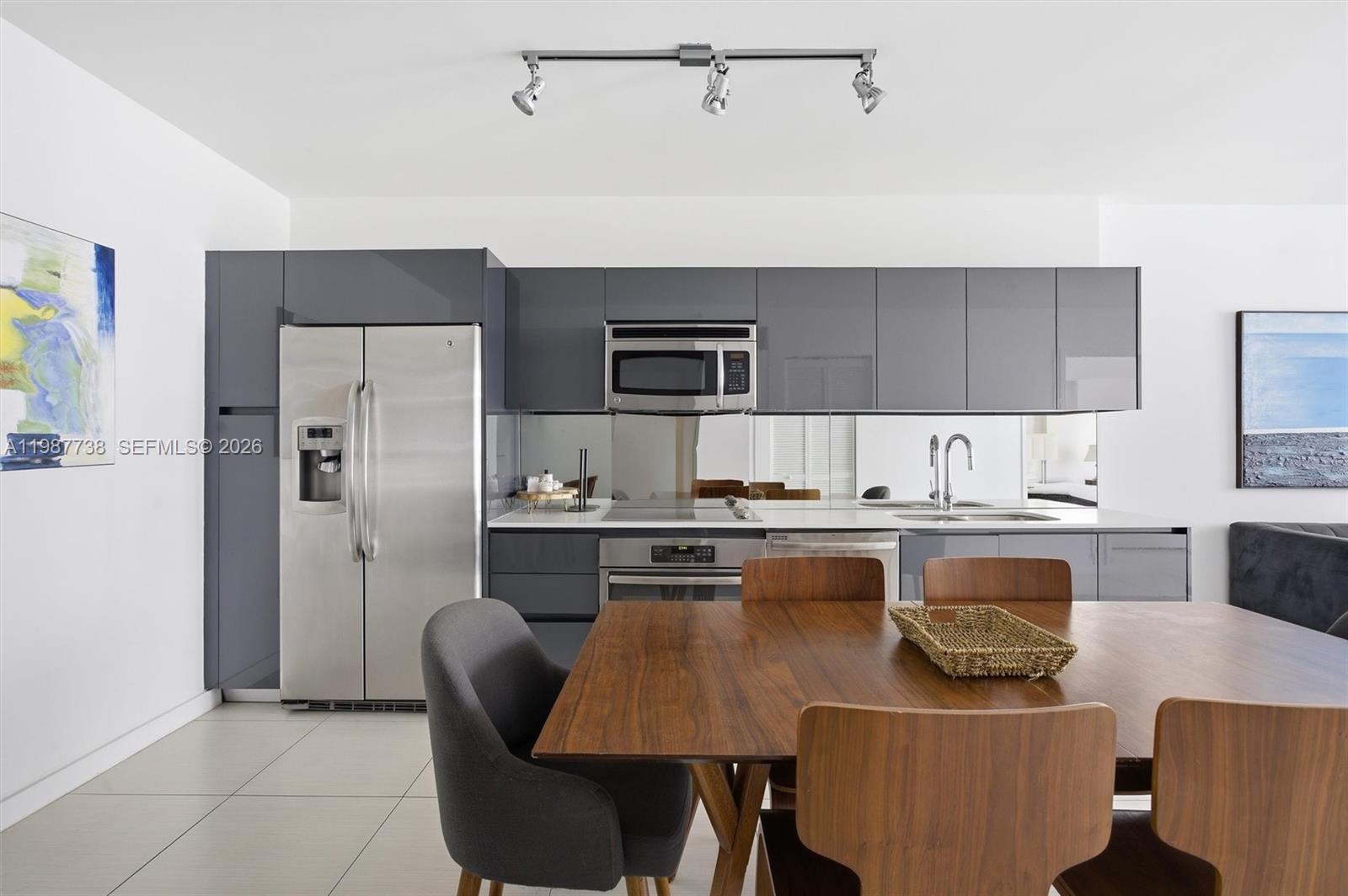 A modern kitchen features gray cabinets, stainless steel appliances, and a wooden dining table — 31 SE 6th St # 2504, Miami FL 33131, MIAMI, FL