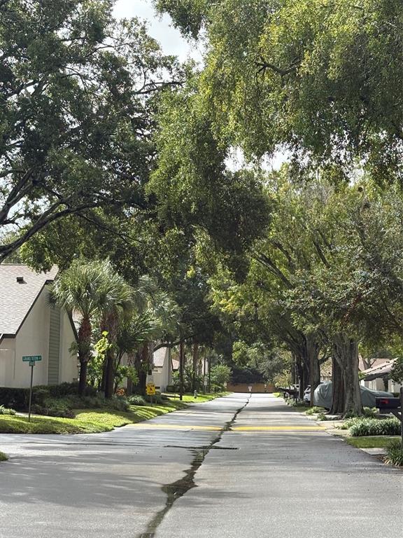A residential street lined with mature trees and houses under a bright, partly cloudy sky — 2336 SUN VALLEY CIRCLE BLDG 20, WINTER PARK, FL