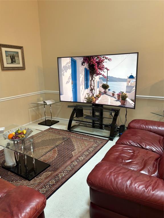 A living room features a large television on a glass stand, a red leather sofa, and a rug — 2336 SUN VALLEY CIRCLE BLDG 20, WINTER PARK, FL