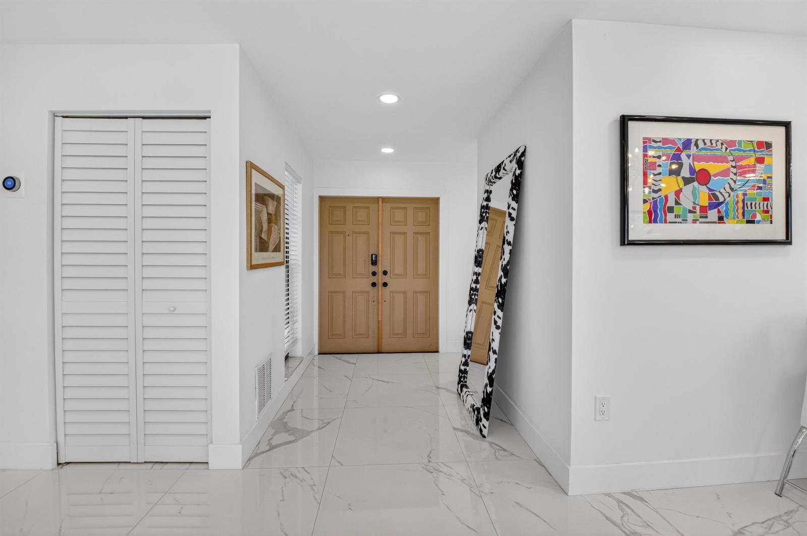 A bright entryway features white walls, marble-look tile flooring, a double door, and a mirror — 6760 Willow Wood Drive # 1204, Boca Raton FL 33434, BOCA RATON, FL