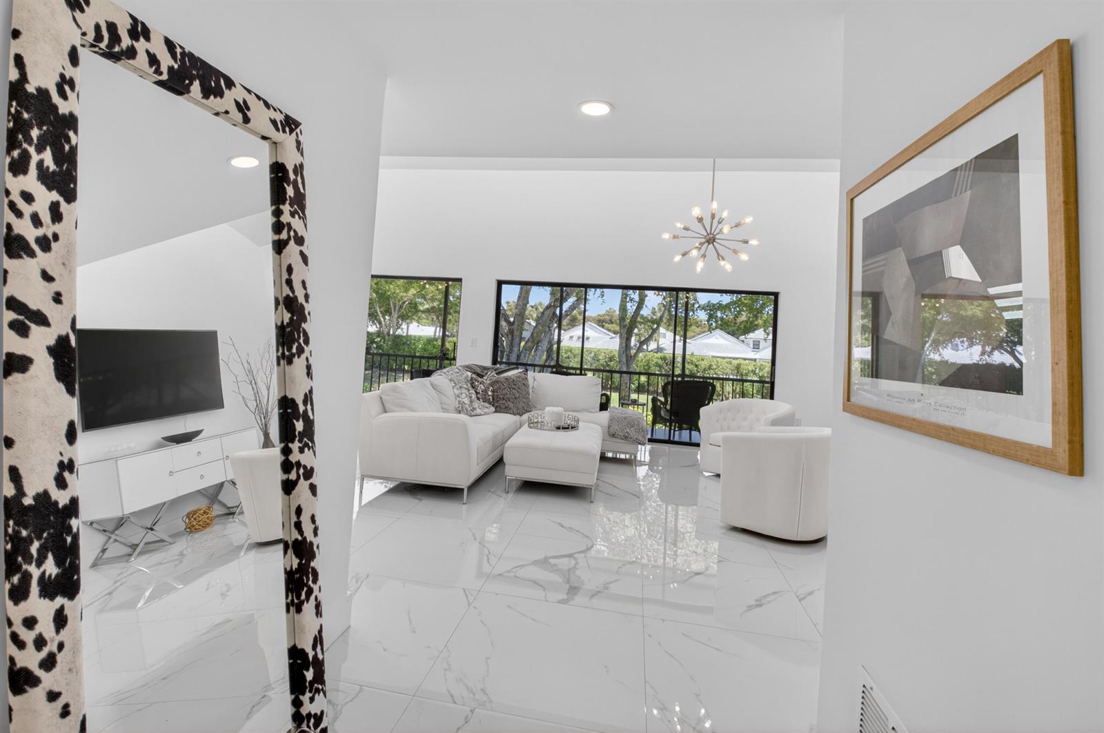 A bright living room features white tile floors, a sectional sofa, and large sliding glass doors — 6760 Willow Wood Drive # 1204, Boca Raton FL 33434, BOCA RATON, FL