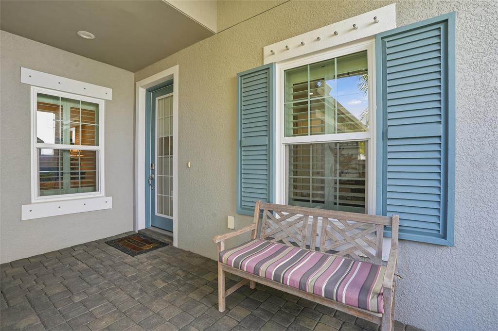 A covered porch features a wooden bench, blue shutters, and a front door with glass — 11655 SOLANO DRIVE, FORT MYERS, FL