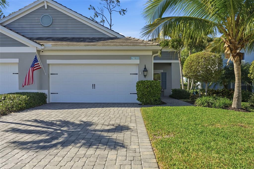 A gray house with a white garage door, a paved driveway, and a palm tree — 11655 SOLANO DRIVE, FORT MYERS, FL