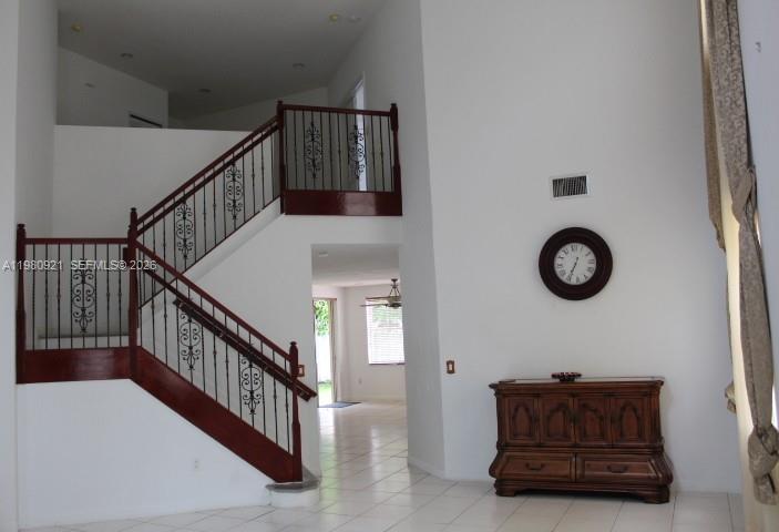 A foyer features a wooden staircase with decorative metal railings and a wooden cabinet — 2313 SW 126th Ave, Miramar FL 33027, MIRAMAR, FL