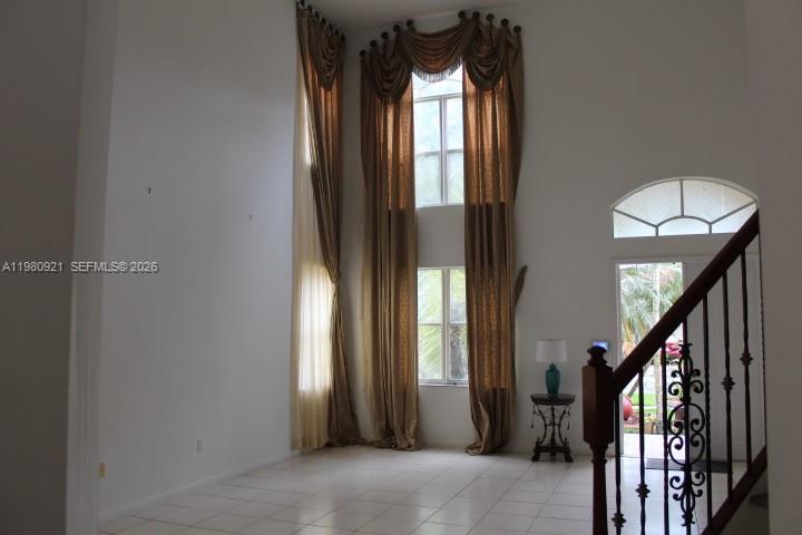 A two-story foyer features tiled floors, tall windows with draped curtains, and a staircase railing — 2313 SW 126th Ave, Miramar FL 33027, MIRAMAR, FL