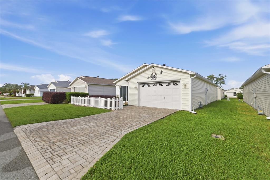 A single-story house with light siding, a white garage door, and a paved driveway — 1714 EL NINO STREET, THE VILLAGES, FL