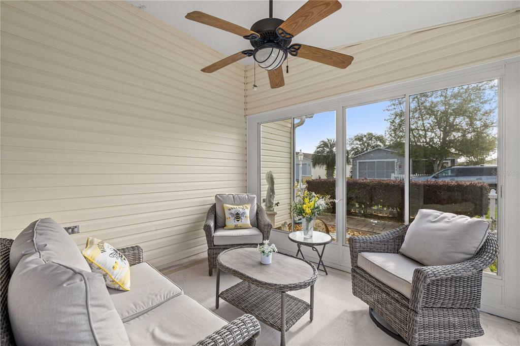 A sunroom features wicker furniture, a ceiling fan, and large windows overlooking a neighborhood street — 1714 EL NINO STREET, THE VILLAGES, FL
