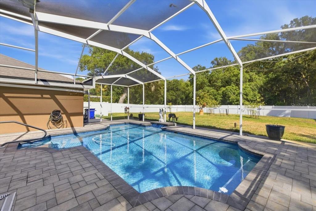 A rectangular swimming pool with a screened enclosure sits on a paved patio — 2818 SHIPSTON AVENUE, NEW PORT RICHEY, FL