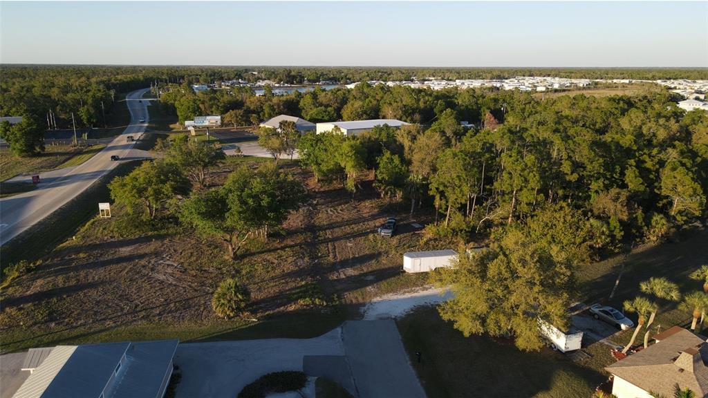An aerial view shows a vacant, wooded lot adjacent to a road and residential area — 12354 SW CO ROAD 769, LAKE SUZY, FL