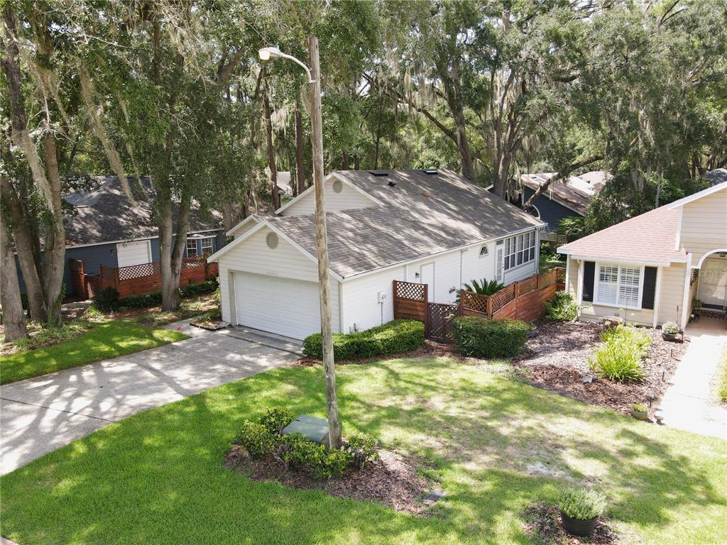 An elevated view shows a white house with a garage, driveway, and surrounding trees — 12314 NW 8TH PLACE, NEWBERRY, FL