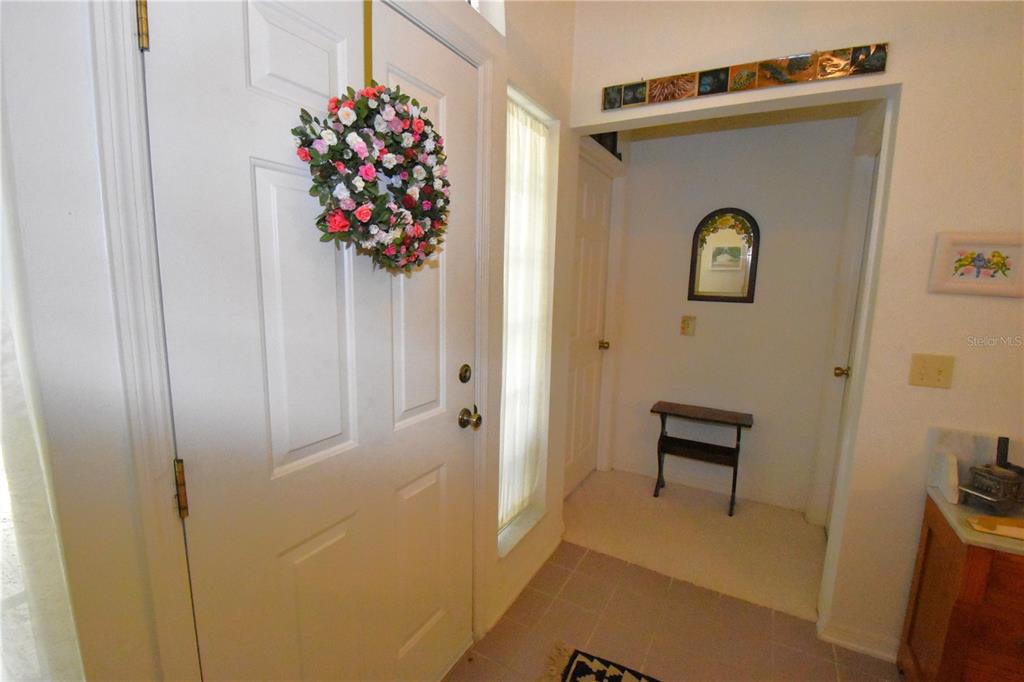 An entryway features a white front door with a floral wreath and tiled flooring — 12314 NW 8TH PLACE, NEWBERRY, FL