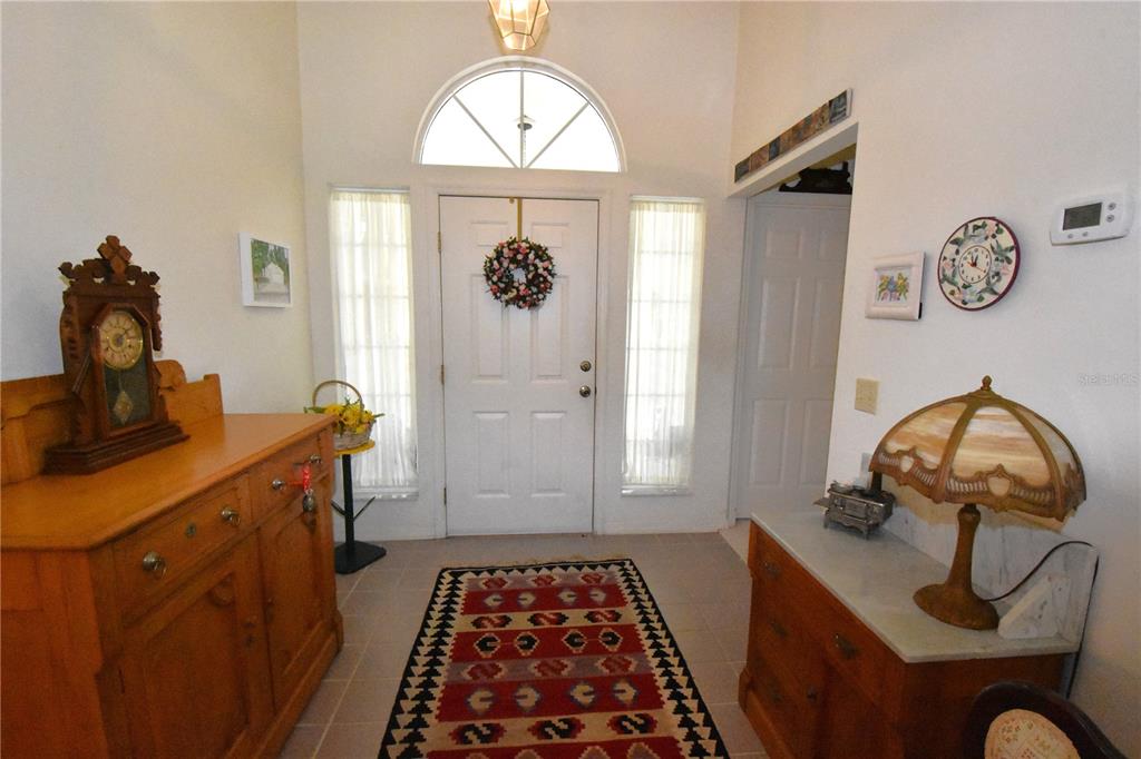 An entryway features a white front door, a patterned rug, and two wooden cabinets — 12314 NW 8TH PLACE, NEWBERRY, FL