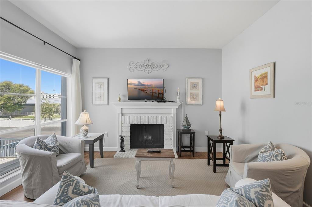A living room features a white brick fireplace, a television, and two armchairs — 175 MEDALLION BOULEVARD UNIT F, MADEIRA BEACH, FL
