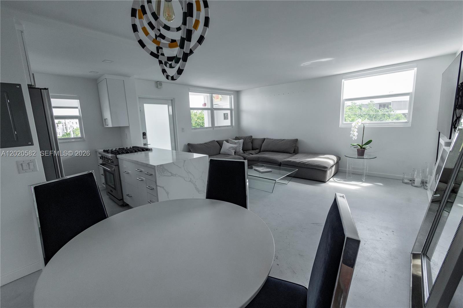 A modern open-concept living area features a kitchen island, dining table, and gray sectional sofa — 301 Jefferson Ave # 4E, Miami Beach FL 33139, MIAMI BEACH, FL