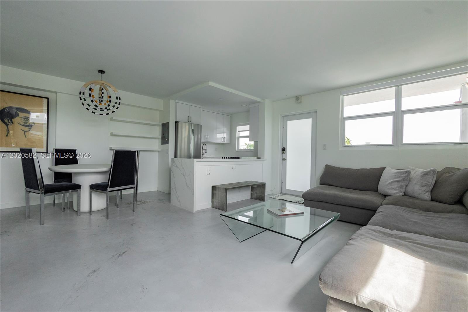 An open-concept living and dining area features white walls, concrete floors, and a modern kitchen — 301 Jefferson Ave # 4E, Miami Beach FL 33139, MIAMI BEACH, FL